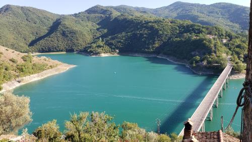 a bridge over a blue lake with mountains in the background at Amazing Lake View in Castel di Tora
