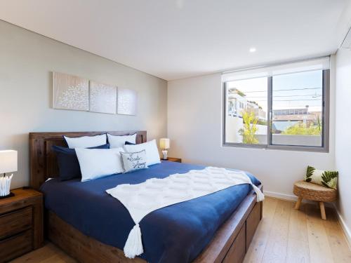 a bedroom with a blue and white bed and a window at The Shoal 104 linen included and under 200m to beach in Shoal Bay