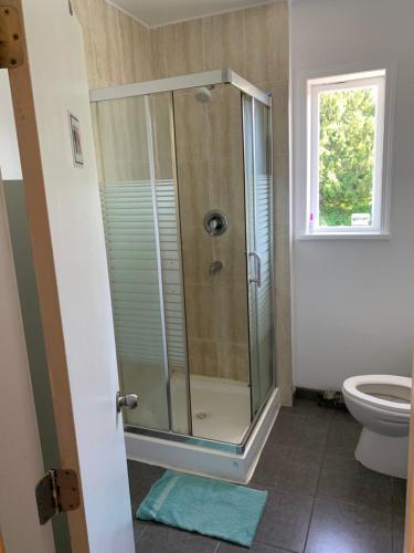 baño con ducha, aseo y ventana en Vancouver Backpacker House, en Burnaby