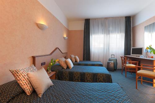 a hotel room with two beds and a desk at Hotel Le Sorgenti in Bolzano Vicentino