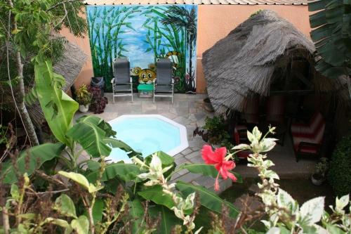 a backyard with a small swimming pool and a hut at Hotel Aurore Lomé in Lomé