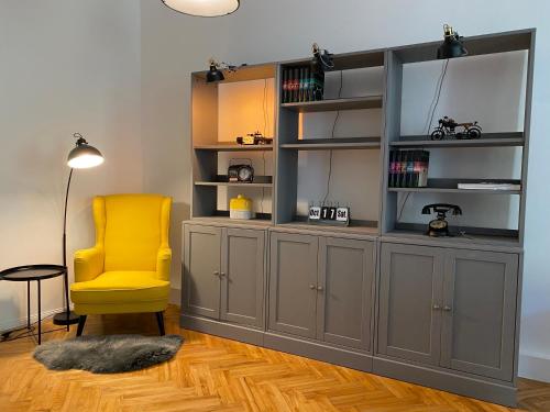 Habitación con estante de libros y silla amarilla en Industrial Apartment Schlossberg, en Linz