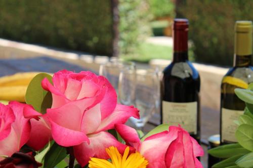a table with a bottle of wine and pink flowers at Casa Vacanze Ribocchi in Campiglia Marittima