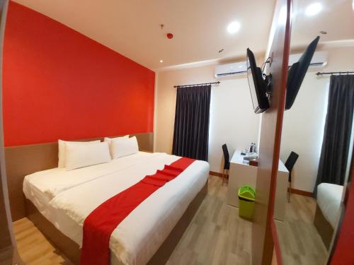 a hotel room with a bed and a flat screen tv at Halogen Hotel Merauke in Merauke