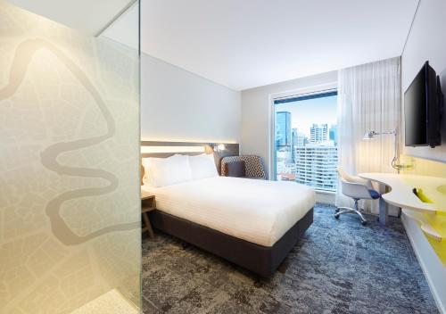 a hotel room with a bed and a desk and a window at Holiday Inn Express Brisbane Central by IHG in Brisbane