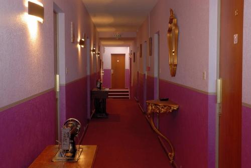 a hallway with pink and purple walls and a hallway with a table at Hotel du Commerce Chez Stéphane in Roumazières