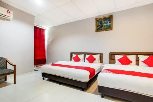 um quarto com 2 camas e almofadas vermelhas em Super OYO 89427 Kavanas Hotel Taiping em Taiping