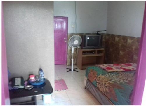 una habitación con una puerta rosa y una habitación con ventilador en Villa Vander en Pasuruan
