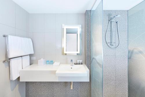 uma casa de banho branca com um lavatório e um chuveiro em Holiday Inn Express Brisbane Central, an IHG Hotel em Brisbane