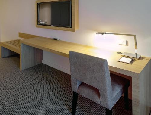 a room with a desk with a chair and a television at Stamford Plaza Sydney Airport Hotel & Conference Centre in Sydney