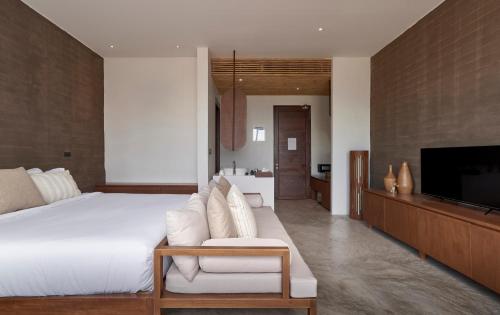 a bedroom with a large white bed and a tv at Chula Beach Resort in Khanom