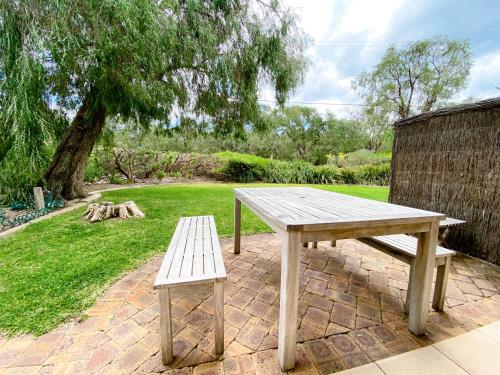 a wooden picnic table and a bench in a park at Whitesands in Dunsborough