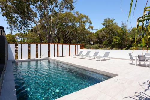 a swimming pool with chairs and a fence at The Beach Houses Holiday Villas in Gold Coast