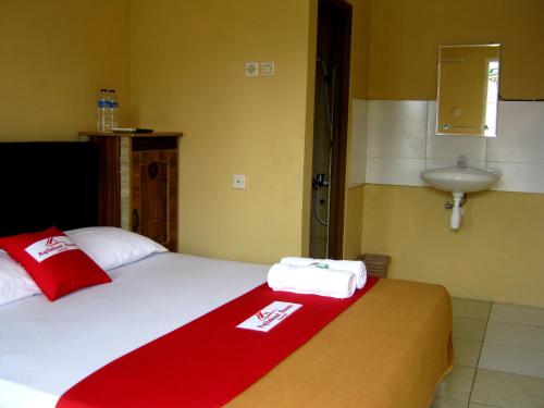 a bedroom with a bed with a red blanket and a sink at Aqilakost n Cafe Gadog Puncak in Bogor
