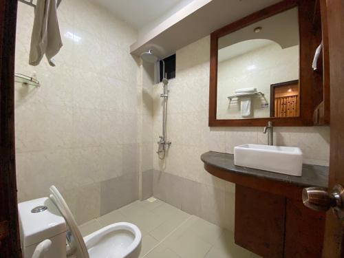 a bathroom with a sink and a toilet and a mirror at Niu Inn & Spa in Hulhumale