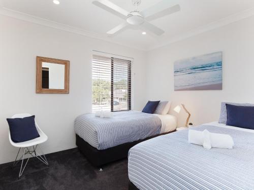 Un dormitorio con dos camas y una silla y una ventana. en Bay Parklands, 68 2 Gowrie Ave - Fully ducted aircon, wifi, pool, tennis court, communal spa, en Shoal Bay