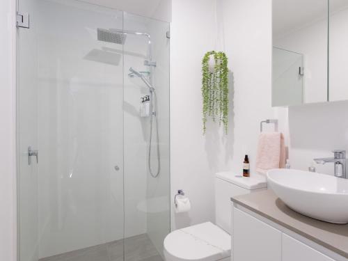 Un baño blanco con ducha y lavabo. en Bay Parklands, 68 2 Gowrie Ave - Fully ducted aircon, wifi, pool, tennis court, communal spa, en Shoal Bay