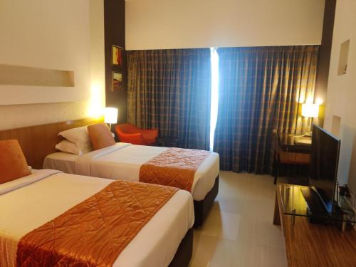 a hotel room with two beds and a television at Hotel Satkar Residency in Thane