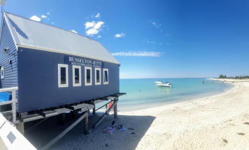 a building on a beach with a boat in the water at Indoyo Retreat in Busselton