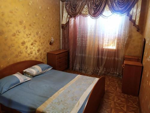 1 dormitorio con 1 cama y una ventana con cortinas en Ильинская 3к посуточно почасово, en Sumy