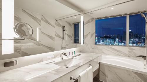 a bathroom with a sink and a tub and a window at Kent Hotel Gwangalli by Kensington in Busan