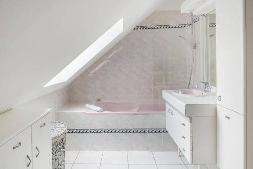 y baño blanco con lavabo y bañera. en LE DUPLEX - Appartement familial cosy, en Saint-Nazaire