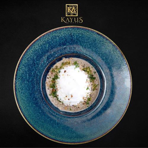 a blue plate with a bowl of food on a table at Kayus in Buşteni