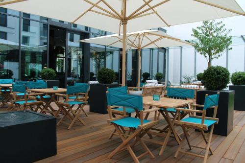 a patio with tables and chairs and an umbrella at Motel One Bremen in Bremen