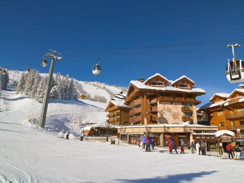 a ski lodge with people standing in the snow next to a ski lift at Hôtel de la Loze in Courchevel