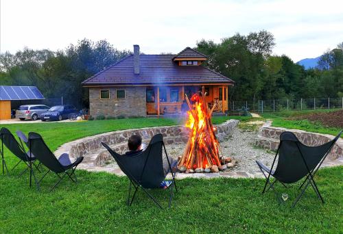 a person sitting in chairs around a fire in front of a house at Atelier Recreation Village in Râşnov