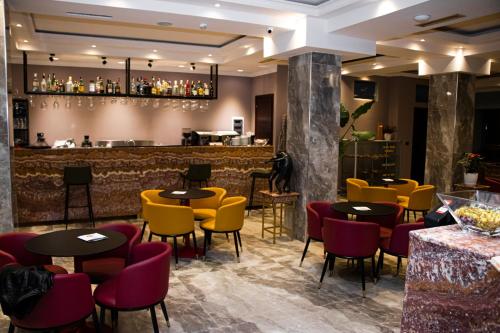 un restaurante con mesas y sillas amarillas y un bar en Hotel Elysee, en Tirana