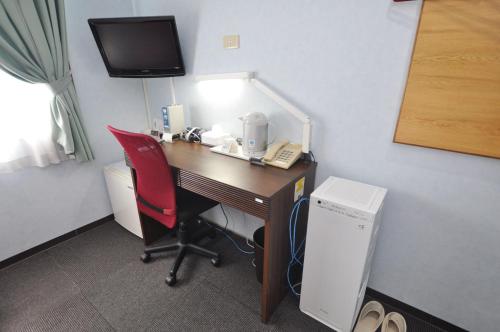 a room with a desk with a phone and a chair at Futsukaichi Green Hotel in Chikushino