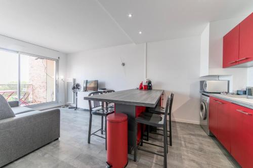 a kitchen with red cabinets and a table with chairs at Appartement à Arcachon à 3 min à pied de la plage in Arcachon