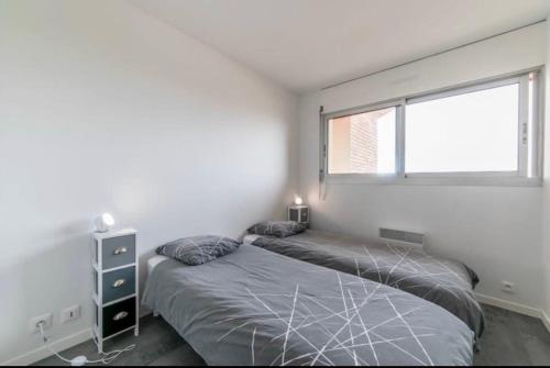 a bedroom with two beds and a window at Appartement à Arcachon à 3 min à pied de la plage in Arcachon