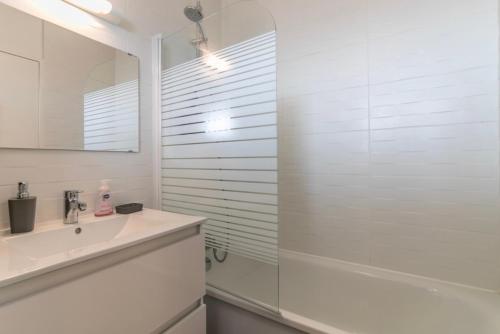 a white bathroom with a sink and a shower at Appartement à Arcachon à 3 min à pied de la plage in Arcachon