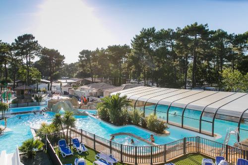 une vue aérienne d'une piscine dans un complexe hôtelier dans l'établissement Mobil Home 4 chambres - Camping Palmyre Loisirs, aux Mathes