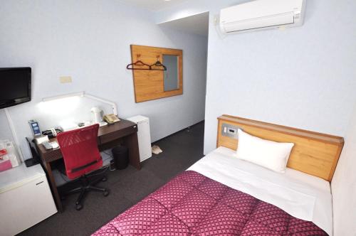 1 dormitorio con 1 cama y escritorio con silla roja en Futsukaichi Green Hotel, en Chikushino