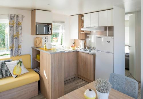 Mobil-Home XXL 4 chambres - Camping La Colline في فيرتون: مطبخ صغير مع أريكة صفراء في الغرفة