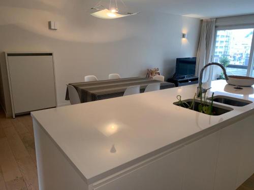 eine weiße Küche mit einem Waschbecken und ein Wohnzimmer in der Unterkunft Casino Beach in Koksijde
