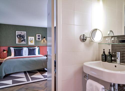 ein Bad mit einem Waschbecken und ein Bett in einem Zimmer in der Unterkunft Park Centraal Den Haag, part of Sircle Collection in Den Haag
