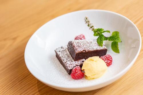 a white plate with a piece of chocolate cake and raspberries at Carndaisy House in Muir of Ord