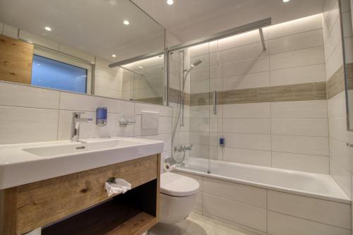 a bathroom with a sink and a tub and a toilet at Matterhorngruss Apartments in Zermatt