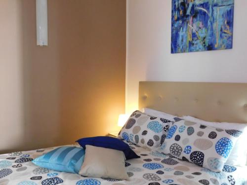a bed with blue and white pillows and a painting at Case Vacanza Elisir in Favignana