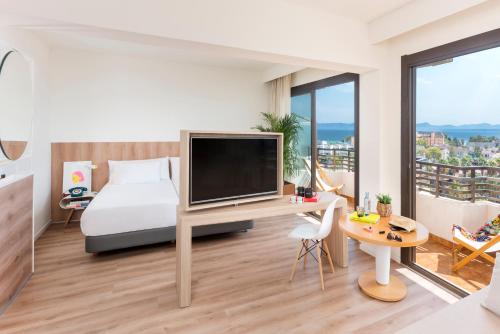 a bedroom with a bed and a desk with a television at INNSiDE by Meliá Alcudia in Port d'Alcudia