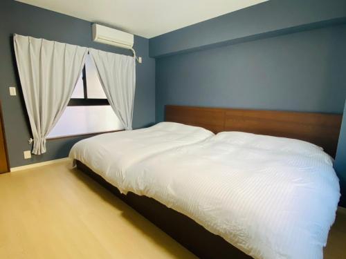 um quarto com uma cama branca e uma janela em Parkside Inn Hakata No4 em Fukuoka