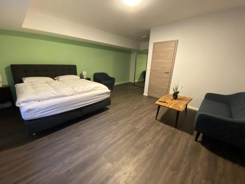 a bedroom with a bed and two chairs and a table at JG Hotel am Schweizerberg in Memmingen