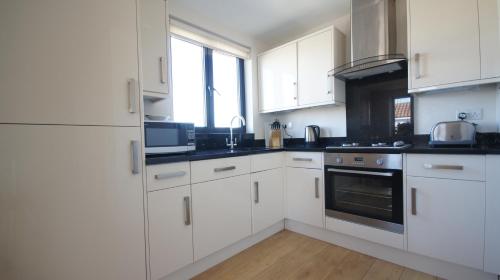 a kitchen with white cabinets and a stove top oven at Crompton Court Apartments in London