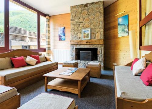 una sala de estar con sofás y una chimenea de piedra. en Appartement F2 au domaine des 100 lacs - piscine - sauna - hammam en Cauterets