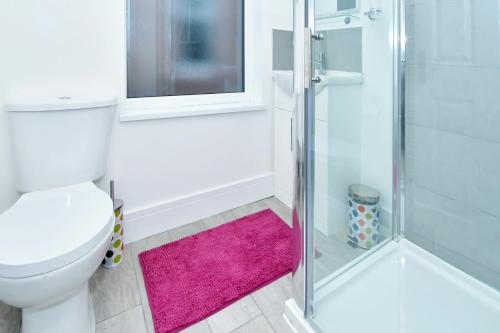 a bathroom with a toilet and a shower with a pink rug at Townhouse @ 543 London Road Stoke in Trent Vale