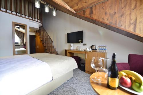 Una habitación de hotel con una cama y una mesa con una botella de vino en Sarikamis Habitat Hotel, en Sarıkamıs